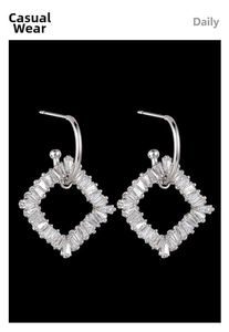 Detailed view of silver dangle earrings with sparkling baguette-cut zirconia on black background