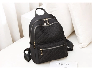 Close-up of black quilted nylon backpack featuring premium gold-tone zippers and hardware