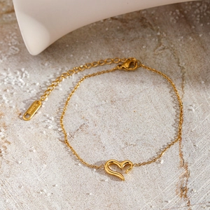 Détail d'un bracelet doré avec pendentif cœur en acier inoxydable poli