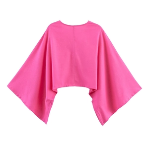 Vue détaillée du haut poncho rose fuchsia avec manches larges et texture tissée