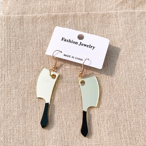 Macro detail of acrylic cleaver earrings with mirror finish on textured fabric background