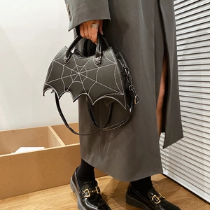 Detailed view of the creative bat wing shaped PU leather handbag held by a model