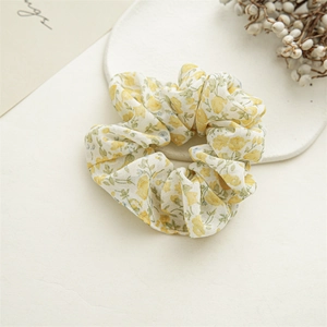 Close-up of yellow floral pattern on chiffon scrunchie with soft pleated texture