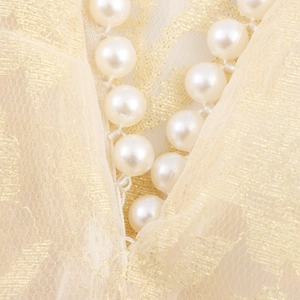 Close-up of elegant white pearl necklace on vintage gold embroidered lace fabric