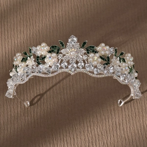 Detailed shot of bridal crown featuring purple pearls, rhinestones and green floral motifs