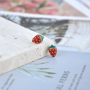 Detailed macro shot of cute red strawberry stud earrings with green leaf enamel finish