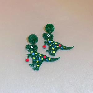 Detailed close-up of acrylic Christmas dinosaur earrings with green glitter and star print
