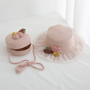 Detailed view of pink straw hat and matching round bag with lace and floral accents