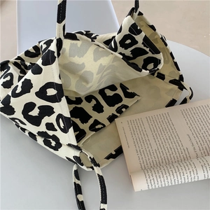 Detailed close-up of leopard print canvas tote bag with book on neutral background