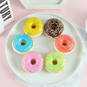 Set de seis coloridas donas artificiales de PU con chispas en un plato blanco