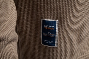 Macro detail of brown waffle knit fabric featuring a fashion trends decorative woven label