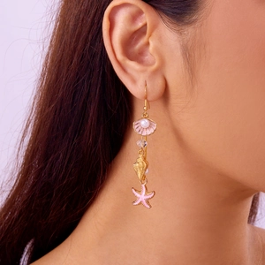 Detail of seashell and starfish drop earrings with pink enamel and pearls on a model