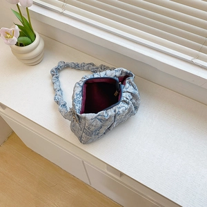 Blue jacquard ruched shoulder bag with burgundy interior and floral home decor