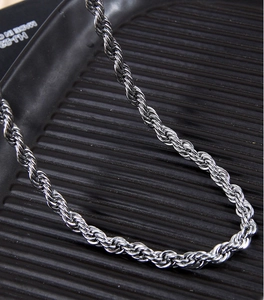 Close-up of a silver twisted rope chain necklace on a black textured jewelry tray