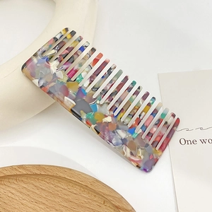 Vintage acetate hair comb with colorful mosaic terrazzo pattern on a clean background
