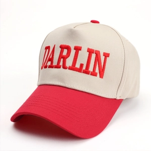 Detail of DARLIN embroidery on a two-tone off-white and red cotton baseball cap