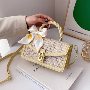 Straw crossbody bag with silk bow and gold lock clasp on minimalist background