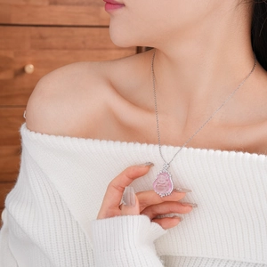 Detail of a pink resin Buddha pendant necklace with sparkling zircon border on a model