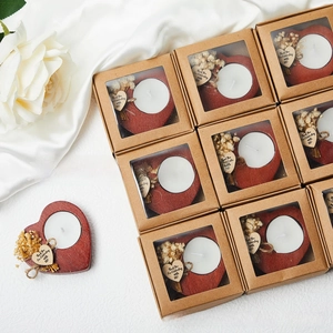 Close-up of heart-shaped wooden candle holders with dried flowers and thank you tags