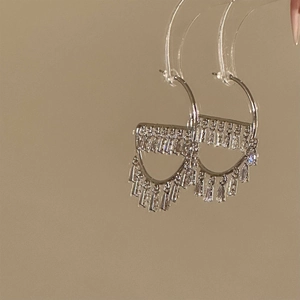 Silver hook earrings with trapezoid cubic zirconia tassels on a transparent display stand