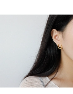 Close-up of a model wearing irregular geometric gold hoop earrings with a polished finish