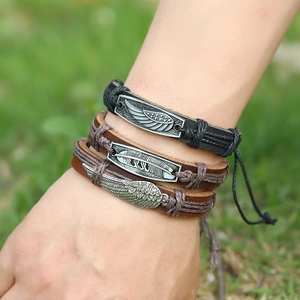 Detail of vintage braided leather bracelets featuring metal feather and leaf charms