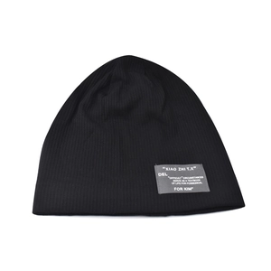 Detailed view of black ribbed knit beanie with small decorative letter patch