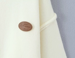 Detailed macro view of the cream knit fabric with a brown leather logo patch