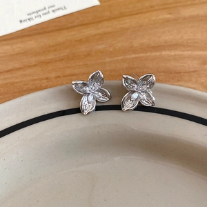 Detailed view of silver flower earrings with zircons on a ceramic plate edge