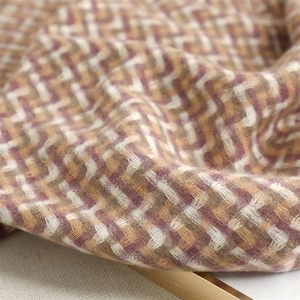 Close-up of thick plaid scarf featuring soft pink, yellow, and brown woven textures