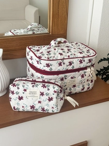 Detailed macro of two-piece floral corduroy cosmetic bags with red ribbon zippers
