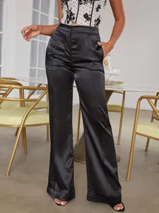 Detail of high-waist black satin wide-leg trousers featuring elegant folded cuffs