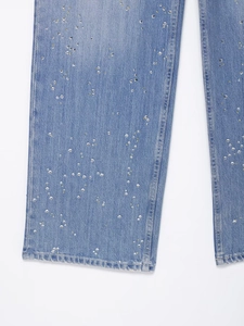 Vue détaillée d'un pantalon en jean bleu orné de strass argentés de haute qualité