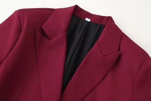 Dettaglio del risvolto del blazer bordeaux con fodera nera e trama in tessuto fine
