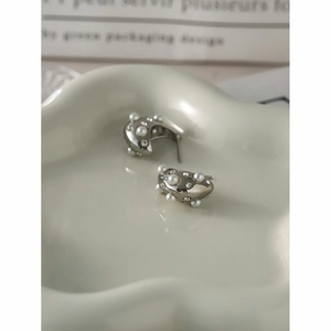 Detailed view of silver water drop earrings with pearls and crystals on a ceramic tray