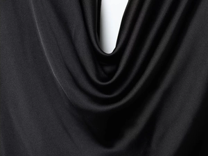 Détail en gros plan de la texture du satin noir avec drapé élégant et éclat soyeux doux