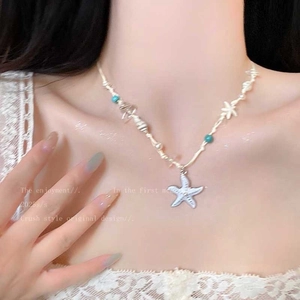 Detail view of starfish pendant with blue and white beads on a woven necklace cord