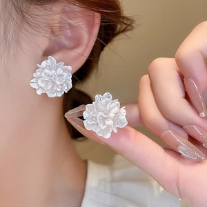 Close-up of white floral earrings with tiered petals worn elegantly by a model