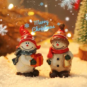 Miniature Christmas snowman figurines with red hats and festive scarves on artificial snow