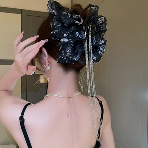 Détail de la grande pince à cheveux noeud noir avec motif floral et pampilles de chaîne