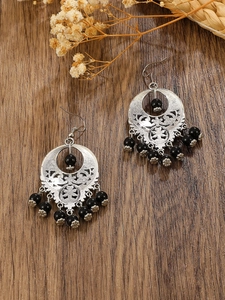 Detail of vintage silver hollow disc earrings with black beads on dark wood
