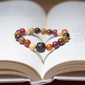 Close-up of multicolor wooden beads bracelet with engraved central master bead and scriptures
