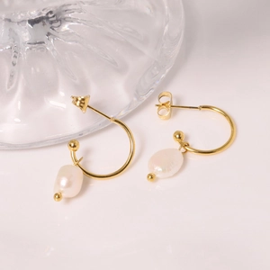 Elegant gold C-shaped metal hoop earrings featuring baroque pearl charms on a soft surface