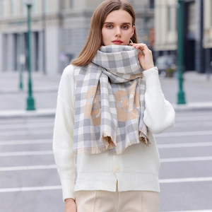 Elegant plaid scarf with beige rose print and tassels worn by a model in city setting