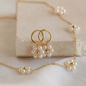 Close-up of gold stainless steel necklace and earrings set with pearl flower charms