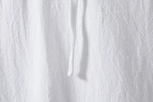 Macro detail of breathable white cotton linen fabric with natural woven texture and drawstring