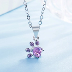 Macro shot of silver cat paw pendant with heart-shaped purple zircon and fine cross chain