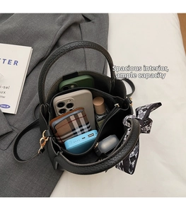 Spacious interior of black lychee texture bucket bag with accessories and center zip pouch