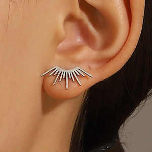 Gros plan sur un ear cuff soleil argenté avec lignes géométriques rayonnantes sur l'oreille