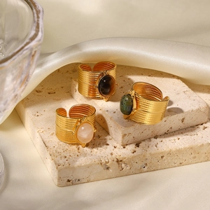 Three 18K gold stainless steel open rings with colored natural stones on stone texture